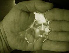 a person holding something in their hand with the reflection of it's face on them