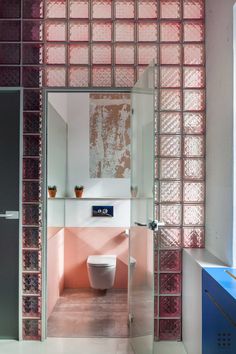 the bathroom is decorated in pink and white with glass blocks on the wall behind it