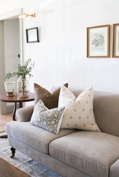 a living room couch with pillows and pictures on the wall above it, along with a coffee table