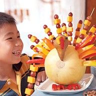 a little boy that is sitting in front of a fake turkey and vegetables on sticks