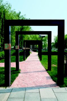 the walkway is lined with black arches and wooden benches on both sides, along with green grass