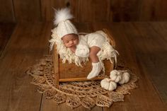 a newborn baby wearing a white hat and diaper is laying on a wooden crate