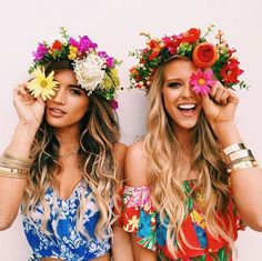 two beautiful women standing next to each other with flowers in their hair and wreaths on their heads