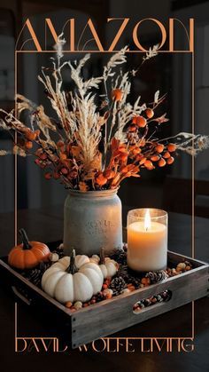 an arrangement of flowers, candles and pumpkins on a tray with the words amzon above it