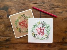 two handmade christmas cards on a wooden table with a red marker and pen next to them