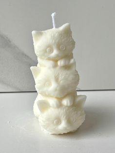 a white candle that is sitting on top of a table next to a cat figurine