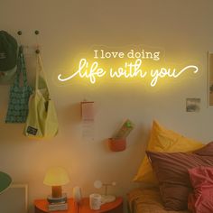 a neon sign that says i love doing life with you on the wall above a bed