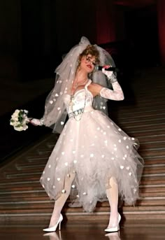 a woman in a white dress and veil is dancing on stage with her hands behind her head