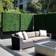 a couch sitting on top of a cement floor next to a fire pit in front of a green wall