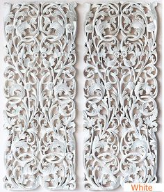 two white carved wood panels with scrolls and flowers on the sides, one is made out of