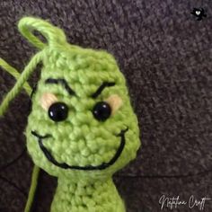 a green crocheted toy with a smiley face