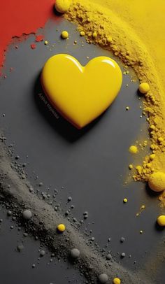 a heart shaped object sitting on top of some yellow and red paint next to it