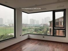 an empty room with wooden floors and large windows looking out onto the cityscape