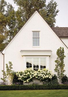 a white house with flowers in the front yard