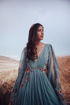 a woman wearing a blue dress standing in a field