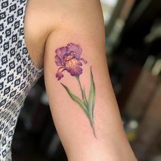 a woman's arm with a purple flower tattoo on the left side of her arm