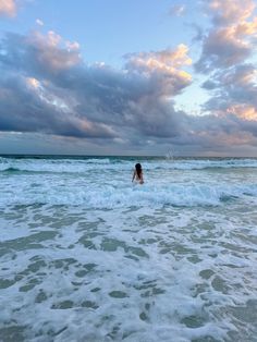 a person standing in the ocean with their back to the camera and arms behind them