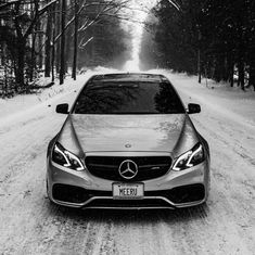 a car parked on the side of a snow covered road in front of some trees