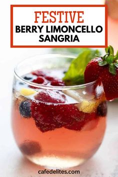 a glass filled with liquid and fruit on top of a white table next to a strawberries