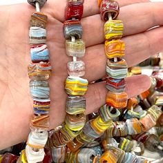 a hand holding several different colored glass beads