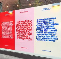 three large posters on the side of a building with words written in different colors and font