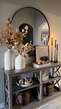 a table with vases, candles and plates on it in front of a mirror