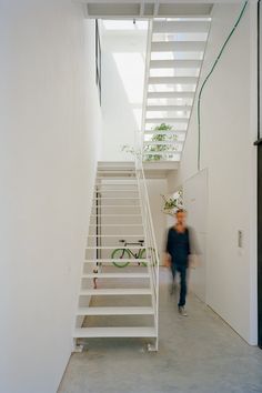 a man is walking down the stairs in a house with white walls and concrete floors