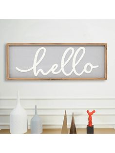 a sign that says hello on it next to some vases and other items in front of a white wall