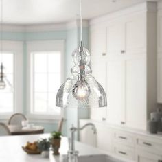 a kitchen with an island, sink and hanging glass light fixture in it's center