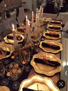 a long table is set with gold plates and place settings, candles in the middle