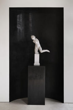 a black and white photo of a statue in the middle of a room with dark walls