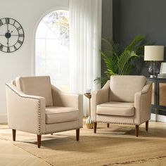 two beige chairs sitting on top of a rug in a living room next to a clock