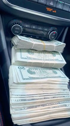 stacks of money sitting in the center console of a car, with radio and dash board