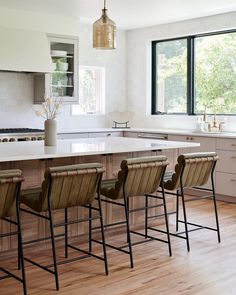 a kitchen with wooden flooring and white counter tops next to a large center island