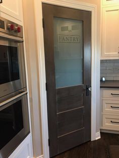 an empty kitchen with white cabinets and stainless steel appliances in the center, along with a pantry door