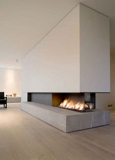 a modern fireplace in the middle of a living room with white walls and wood floors