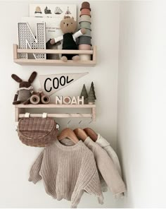 two wooden shelves holding stuffed animals and sweaters on top of each shelf in a white room