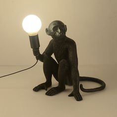 a monkey lamp sitting on the ground with a light attached to it's back