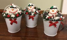 three buckets filled with snowmen sitting on top of a wooden table