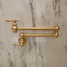 two brass towel bars on a marble wall with white and black tiles in the background