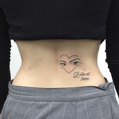 a woman's stomach with an eye and heart tattoo on her lower back side