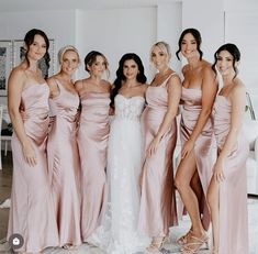 a group of women standing next to each other in pink dresses and one woman wearing a white dress