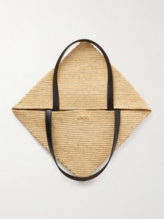 a straw bag with black straps hanging on a white wall next to a handbag