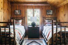 two beds in a room with wooden walls