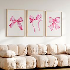 two pink bows are hanging on the wall next to a couch in a living room