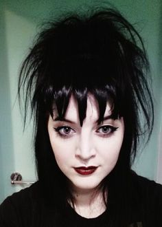 a close up of a person with black hair and makeup holding a cell phone in their hand