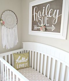 a white crib with a pillow on top of it and a sign above the crib