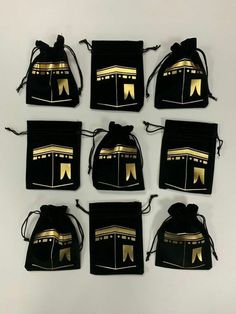 six black velvet drawsacks with gold foiled designs on the front and back