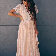 a woman standing in front of a wall wearing a dress