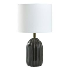 a black glass lamp with a white shade on the base and a light bulb in front of it